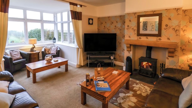A cozy living room with a fireplace, a television, and comfortable seating. - Dilston House (Whitby)