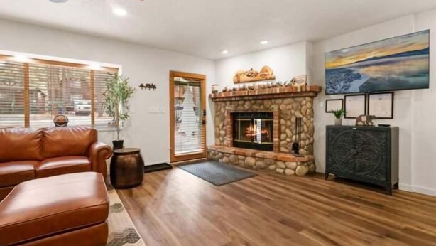 A living room with a stone fireplace, leather sofa, and wooden flooring. - The Cozy Moonridge Cabin (Big Bear Lake)