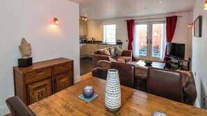 Una sala de estar moderna con una mesa de comedor de madera, un sofá y un televisor.