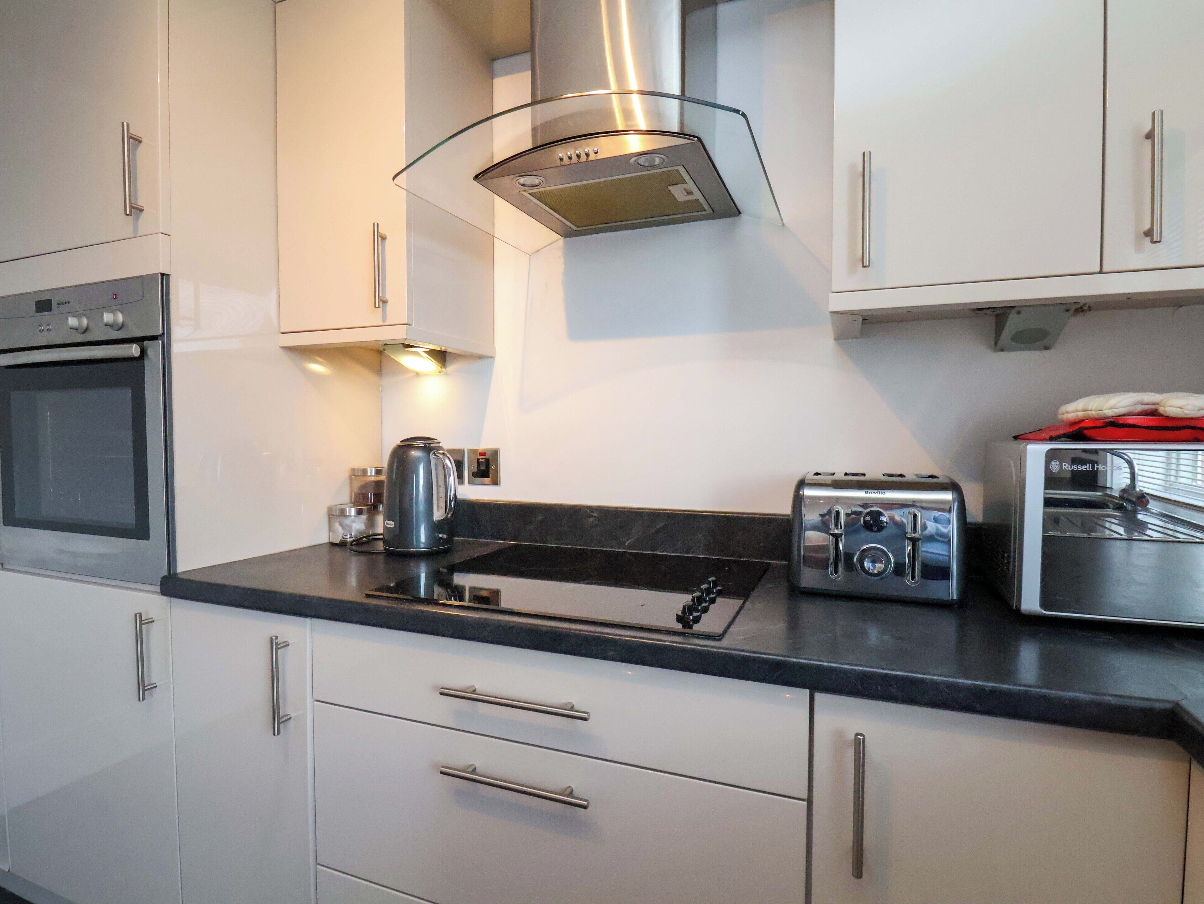 A modern kitchen with stainless steel appliances, a gas stove, a kettle, and a toaster.