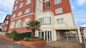 Un edificio de varios pisos con fachada de ladrillo, ventanas amplias y entrada a un estacionamiento.