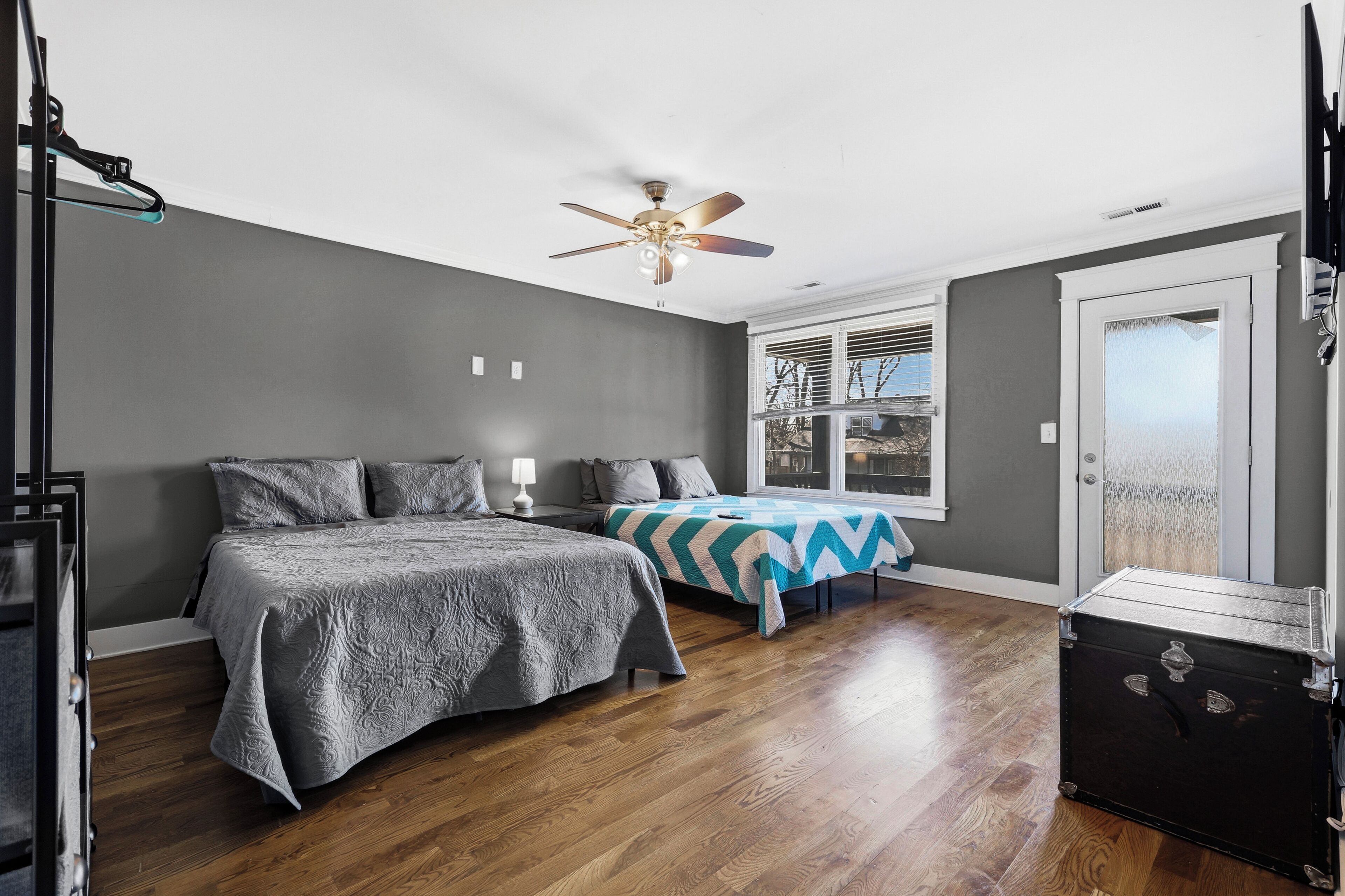 A bedroom with a bed, a nightstand, a dresser, a ceiling fan, and a window with blinds.