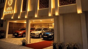 A hotel with a modern facade, a red carpet entrance, and multiple cars parked in the driveway. - Liza Royale Hotel  (Chennai)