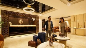 A hotel lobby with a reception desk, a modern chandelier, and a seating area with a vase of flowers. - Liza Royale Hotel  (Chennai)