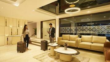 A modern hotel lobby with a sofa, a coffee table, a reception desk, and a large window.