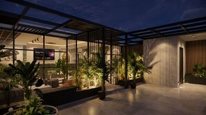 Un espace intérieur moderne, doté d’une cloison en verre, de plantes en pot et d’un coin salon.