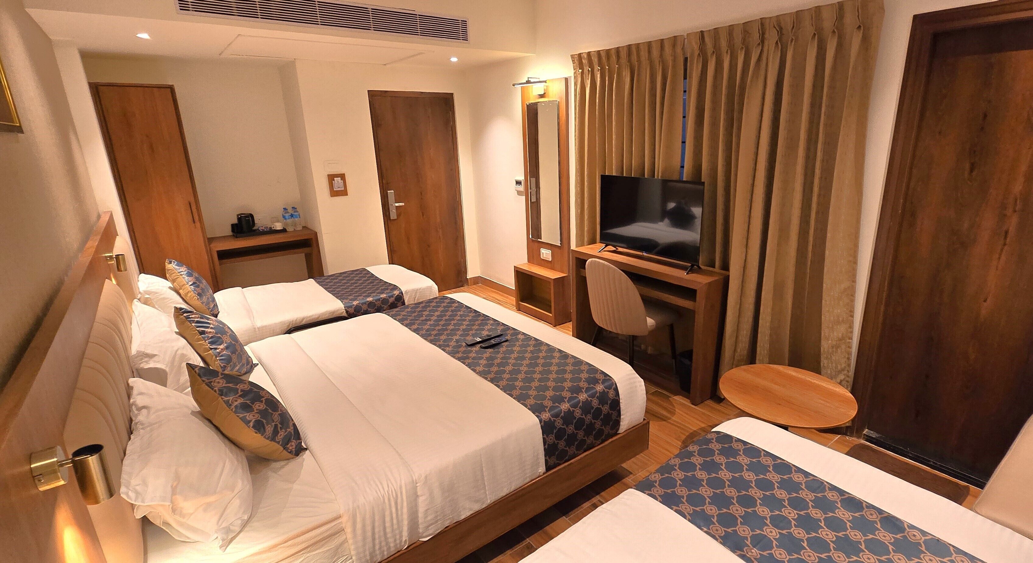 A hotel room with two beds, a TV, a desk, and a chair.