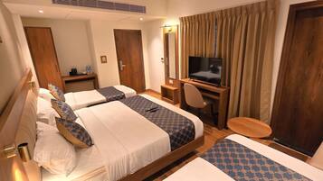 A hotel room with two beds, a TV, a desk, and a chair.