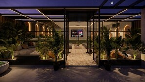 A modern interior with a central seating area, a TV screen, and potted plants.