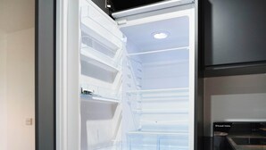 Ein offener Kühlschrank mit mehreren transparenten Fächern und einer eingebauten Mikrowelle.
