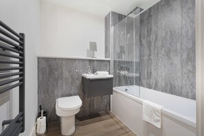 A modern bathroom with a toilet, sink, shower, and bathtub. - Modern 1-Bed Apartment Near Liverpool City Centre (Merseyside)