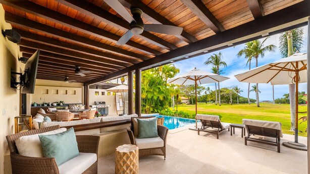 Un espacio al aire libre cubierto con mobiliario de mimbre, una piscina y vistas a un campo de golf.
