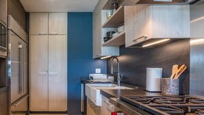 Una cocina moderna con electrodomésticos de acero inoxidable, armarios de madera y una pared de acento azul.
