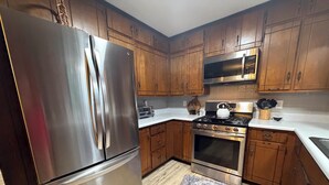 A kitchen with wooden cabinets, stainless steel appliances, and a patterned rug.