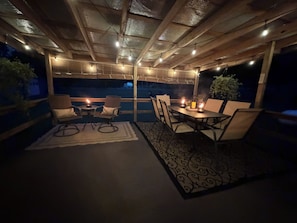 Eine Terrasse im Freien mit Holzmöbeln, Lichterketten und Kerzen.