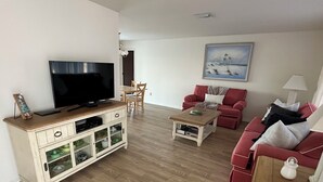Olohuone, jossa on televisio, puinen kaappi, punainen sohva ja seinällä taulu.