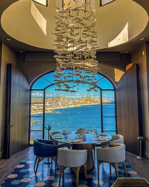 A dining area with a table set for four, a view of the sea, and a hanging fish sculpture. - Luxury 2 Bedroom Villa in Vista Encantada, Cabo San Lucas (Cabo San Lucas)