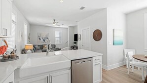 A modern kitchen with white cabinetry, a dishwasher, and a dining area with a round table and chairs. - Bikes*Pool&Hottub*Walk2Beach (Santa Rosa Beach)