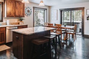A kitchen with wooden cabinets, a granite countertop, a clock, and a dining area with a table and chairs. - Spacious 4 Season Mountain Cabin w/hot tub in Lead--Main Level Entry & Living (Lead)
