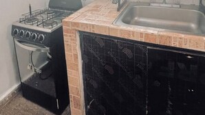 Une cuisine de taille réduite équipée d’une cuisinière à gaz, d’un four et d’un évier.