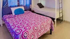 Une chambre avec un lit superposé, une couvre-lit à motifs, des rideaux et une échelle.