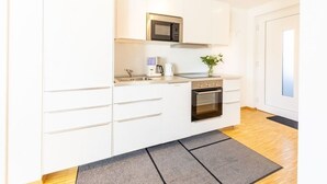 Una cocina moderna con armarios blancos, microondas integrado, cafetera y horno.