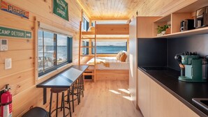 A cabin with a bunk bed, a small kitchen, a dining area, and a view of the water. - Direct Waterfront Cabin Sunset Views 2 (Fort Walton Beach)