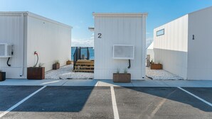 A row of white modular buildings with numbered doors, a paved area in front, and a view of the sea in the background. - Direct Waterfront Cabin Sunset Views 2 (Fort Walton Beach)