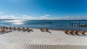 A beach with wooden lounge chairs and a wooden deck. - Direct Waterfront Cabin Sunset Views 2 (Fort Walton Beach)