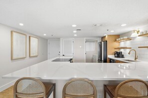 Una cocina moderna con una isla grande, muebles blancos y una cafetera.