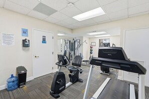 A fitness room with exercise equipment, a water cooler, and a sign detailing room rules. - 1st floor gulf-front condo in Ft Walton Bch FL (Fort Walton Beach)
