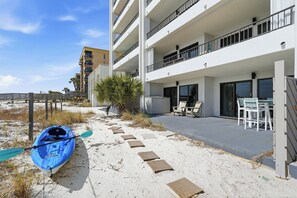 A beachfront hotel with a kayak on the sand, outdoor seating, and a wooden walkway. - 1st floor gulf-front condo in Ft Walton Bch FL (Fort Walton Beach)