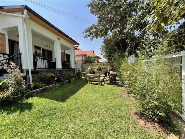 A residential property with a covered porch, a stone retaining wall, and a small garden area with a wooden bench.