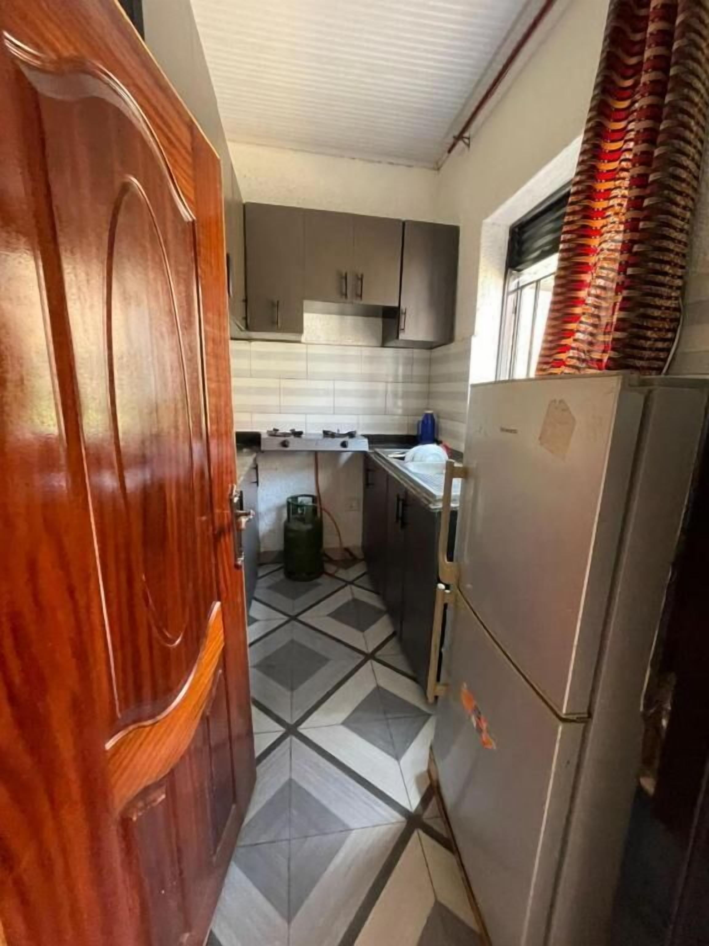 A kitchen with a tiled floor, a refrigerator, and cabinets.