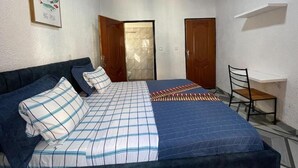 Een slaapkamer met een bed, een bureau en twee deuren.