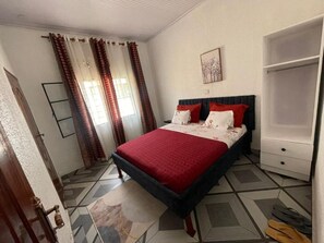 A bedroom with a bed, a wardrobe, and a window with curtains.