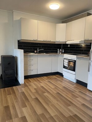 A modern kitchen with white cabinets, a black backsplash, and a wood floor. - Leilighet i solfylte Mandal (Agder)