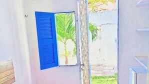 A bedroom with a bed, a window with blue shutters, and an air conditioning unit on the wall. - Pousada Refúgio Praia & Café (Beberibe)