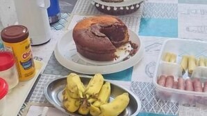 A table with food items, a blue water bottle, a white kettle, and a stainless steel sink. - Pousada Refúgio Praia & Café (Beberibe)