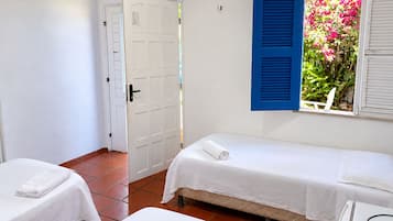 Una stanza con due letti, una porta bianca e una finestra con persiane blu.