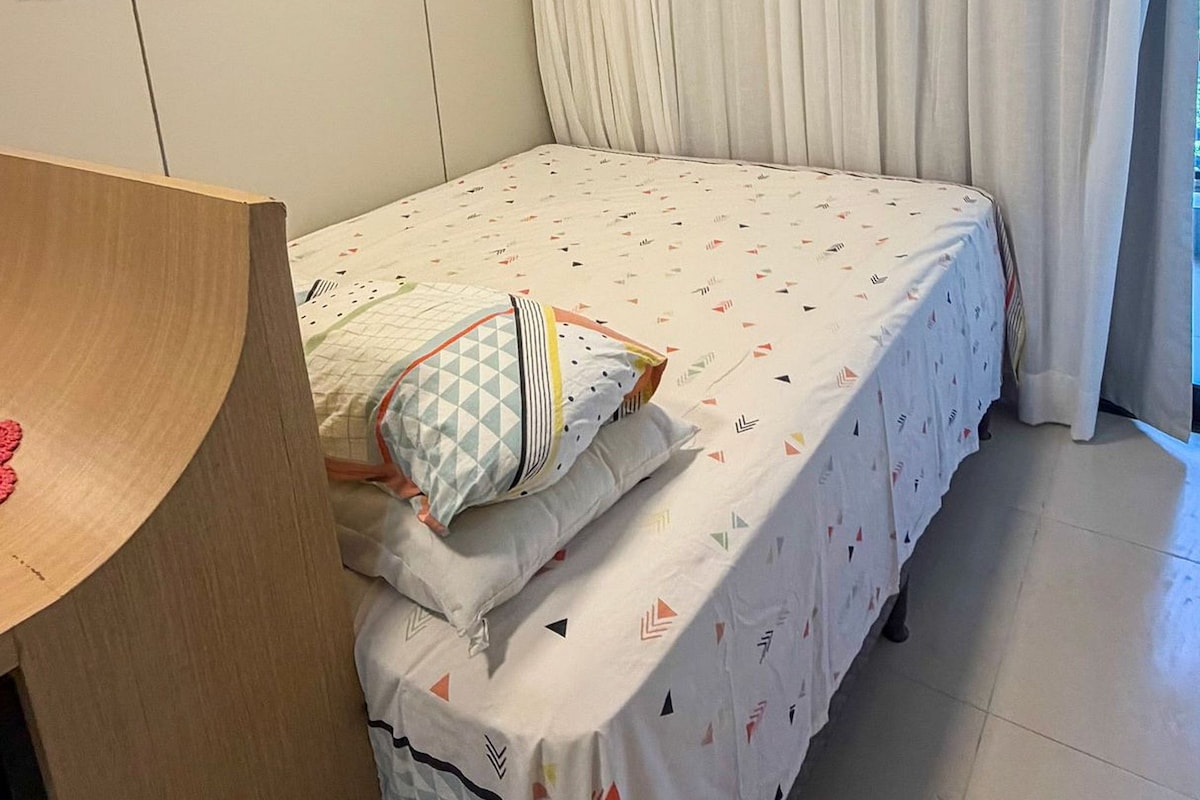 A bedroom with a bed, a desk, and an air conditioning unit.