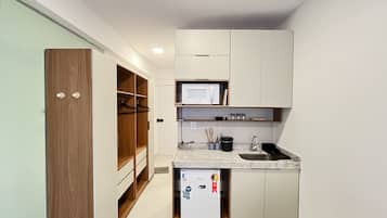 A compact kitchen with a microwave, sink, and storage cabinets.