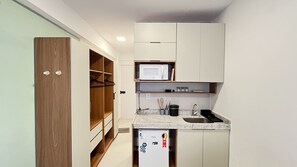 A compact kitchen with a microwave, sink, and storage cabinets. - Terrazza Beach Residence - Praia dos Carneiros (Tamandaré)