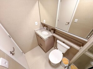 A bathroom with a toilet, sink, mirror, and a shower area. - Terrazza Beach Residence - Praia dos Carneiros (Tamandaré)