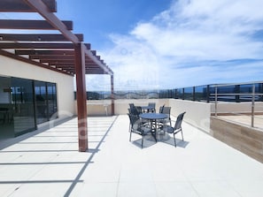A rooftop terrace with a pergola, a table with chairs, and a view of the landscape. - Terrazza Beach Residence - Praia dos Carneiros (Tamandaré)