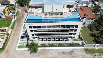 A multi-story hotel with a rooftop pool, a parking area, and a landscaped garden.