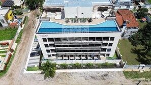 A multi-story hotel with a rooftop pool, a parking area, and a landscaped garden. - Terrazza Beach Residence - Praia dos Carneiros (Tamandaré)