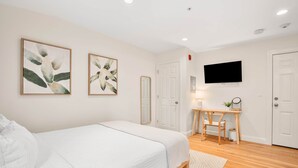 Une chambre à coucher avec un lit, un bureau et une télévision.