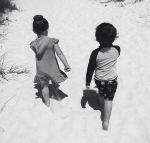 Dos niños caminando sobre arena.