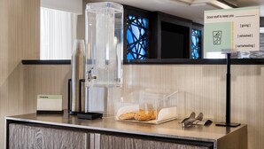 A hotel reception area with a coffee machine, a glass container with cookies, and a sign with amenities. - Best Western Plus Liberal Hotel & Suites (Liberal)